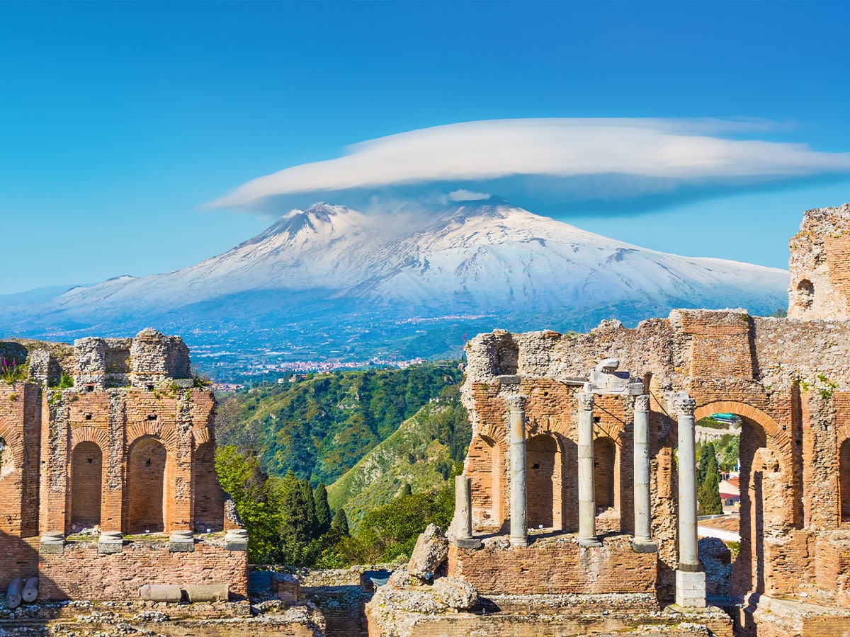 Ancient Greek theatre in Taormina on background of Etna Volcano, Sicily, Italy.